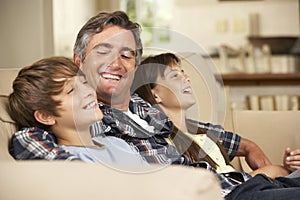 Father And Two Children Sitting On Sofa At Home Watching TV Together