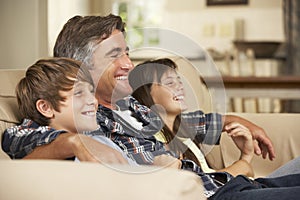 Father And Two Children Sitting On Sofa At Home Watching TV Together