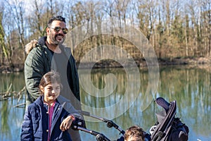 Father with two children is walking along the Aare river in springtime