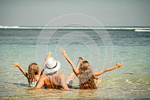 Father and two daughters sitting at the beach