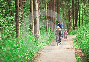 Father with two kids riding bikes in nature