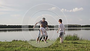 Father and two son playing football on the beach at the day time. Concept of friendly family.