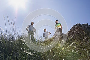 Father with two sons (7-9 10-12) on mountain top low angle vieW