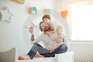 Father of two sons playing with a toy plane