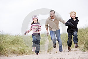 Father and two young children running at beach