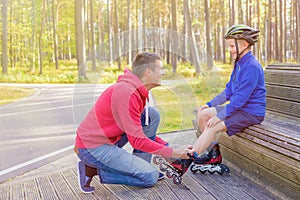 Father tying sons roller skates