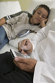 Father Using PDA on sofa with Son Listening to Music close up of hands of father