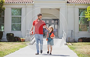 Father walking son to school. Parent and pupil of primary school schoolboy. Dad and cild go beginning of lessons.