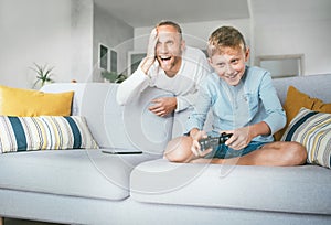 Father watching his son playing TV video game using the gamepad