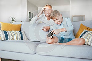 Father watching his son playing TV video game using the gamepad