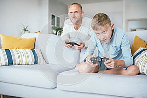 Father watching his son playing TV video game using the gamepad