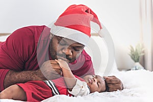 Father wearing a red Christmas hat and kissing hand  his 4-month-old baby newborn son