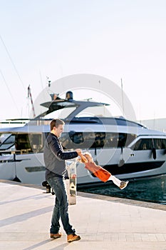 Father is whirling his baby girl in front of a big boat on a pier