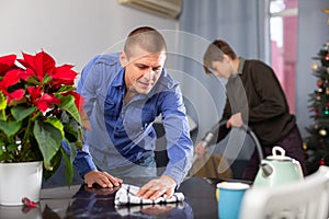 Father wipes the table, son vacuums the room before celebrating new year