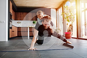 Father working out, doing single arm plank with his jolly baby riding on him