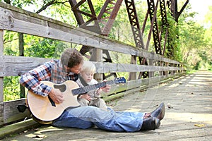 Father and Young Child Playing Guitar Outside at Park