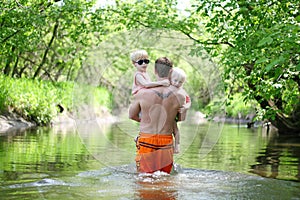 Father and Young Children Walking in River in Forest