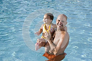 Father and young daughter enjoying swimming pool
