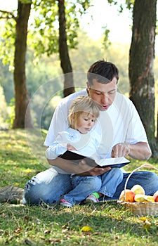 Father with a young daughter read the Bible in nature