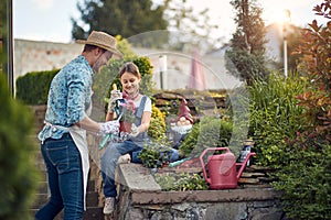 Father and young girl child assisting with re planting a flower from a flower pot, sitting by the flower garden by the house,