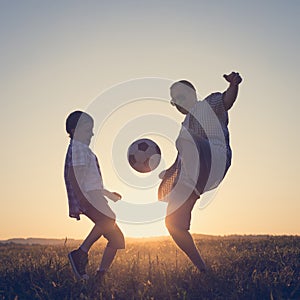 Father and young little boy playing in the field  with soccer ball