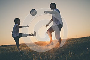 Father and young little boy playing in the field  with soccer ball