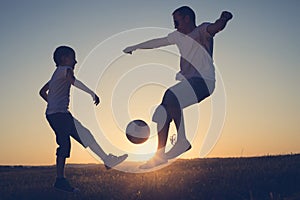 Father and young little boy playing in the field  with soccer ball