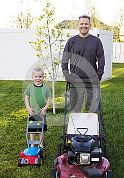 Father and Young Son mowing the lawn together