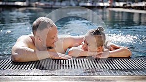 Father with young son playing and having fun on summer vacation in outdoor swimming pool. Dad teaches his son to swim