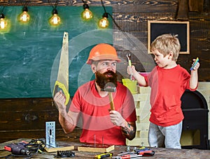 Fatherhood concept. Boy, child cheerful playing and learning to use tools with dad. Father, parent with beard in