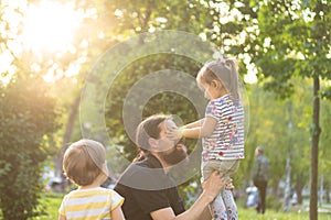 Fatherhood, parenthood, childhood, caring, summer and leisure concept - young dad with beard and long hair in black t