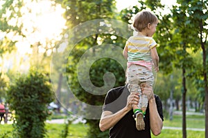 Fatherhood, parenthood, childhood, caring, summer and leisure concept - young dad with beard and long hair in black t