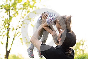 Fatherhood, parenthood, childhood, caring, summer and leisure concept - young dad with beard and long hair in black t