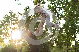 Fatherhood, parenthood, childhood, caring, summer and leisure concept - young dad with beard and long hair in black t