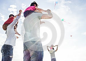 Fathers with children flying with kites and having fun on the beach - Families friends playing with sons on summer vacation -