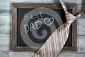 Fathers day concept, Best Dad written on chalkboard with striped tie on wooden background