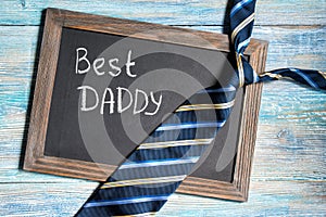 Fathers day concept, Best Daddy written on chalkboard with blue striped tie on wooden background