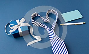 Fathers day concept, tie in heart shape with gift box and card on blue background