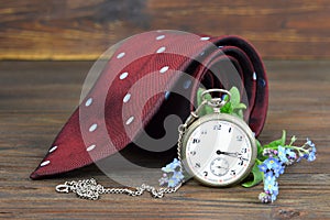 Fathers Day gift. Tie, flowers and vintage pocket watch on wooden background