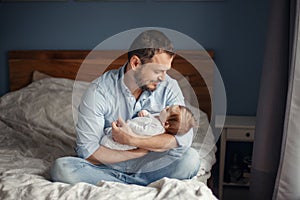 Fathers Day. Middle age Caucasian father with sleeping newborn baby girl. Parent holding child daughter son on hands. Authentic