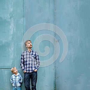 Fathers day square mockup. Dad and son standing together near blue wall and looking up. Parenting, two generations concept. Copy