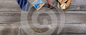 Fathers day top border concept with blue dress tie, hammer, baseball items and a gift box on rustic wooden background