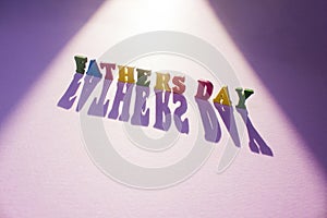 Fathers Day wooden letters in the sun on purple background