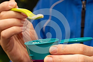 Fathers hand feeding little baby first solid food. Holding a spoon with rice cereal porridge