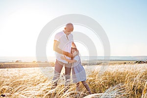 Fathrer and cute daughter hugging outside in golden field