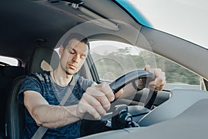 Fatigue of sleeping driver driving at speed while holding wheel while driving on highway in forest. Front view of exhausted man. photo