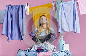 Fatigue woman looks away, stands near basket with pile of laundry