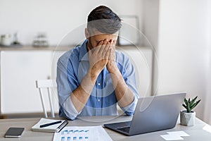 Fatigue From Work. Stressed male entrepreneur covering face with hands at workplace