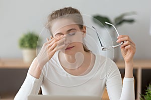 Fatigued girl taking off glasses rubbing eyes feeling eye strain