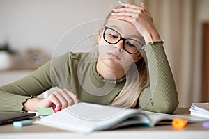 Fatigued girl teenager sitting in front of book